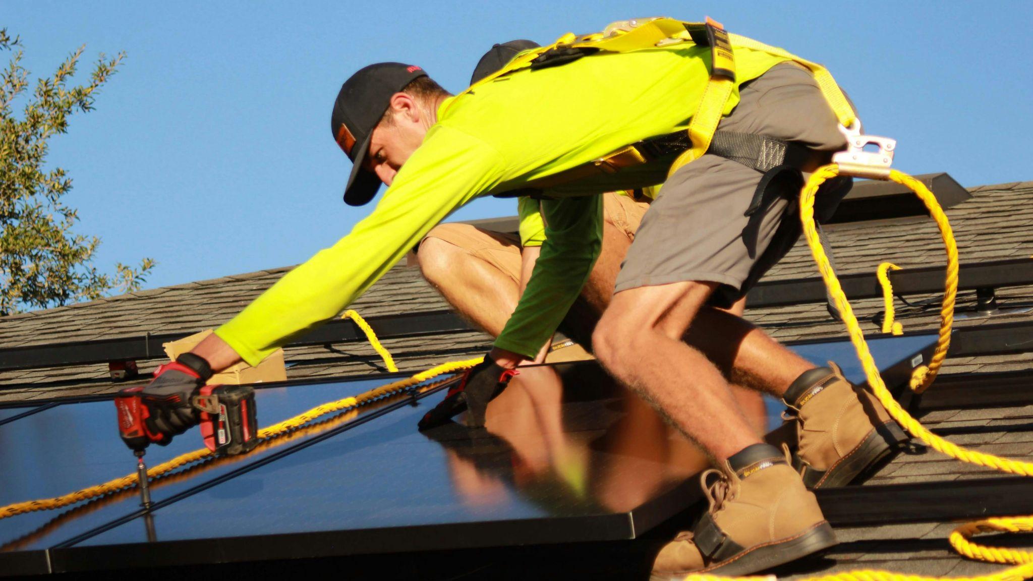 Solar battery installers working on a residential rooftop in NSW